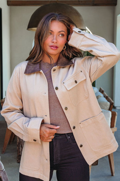 A woman models the Sandstone Contrast Denim Shacket indoors, holding her hair back and glancing to the side.