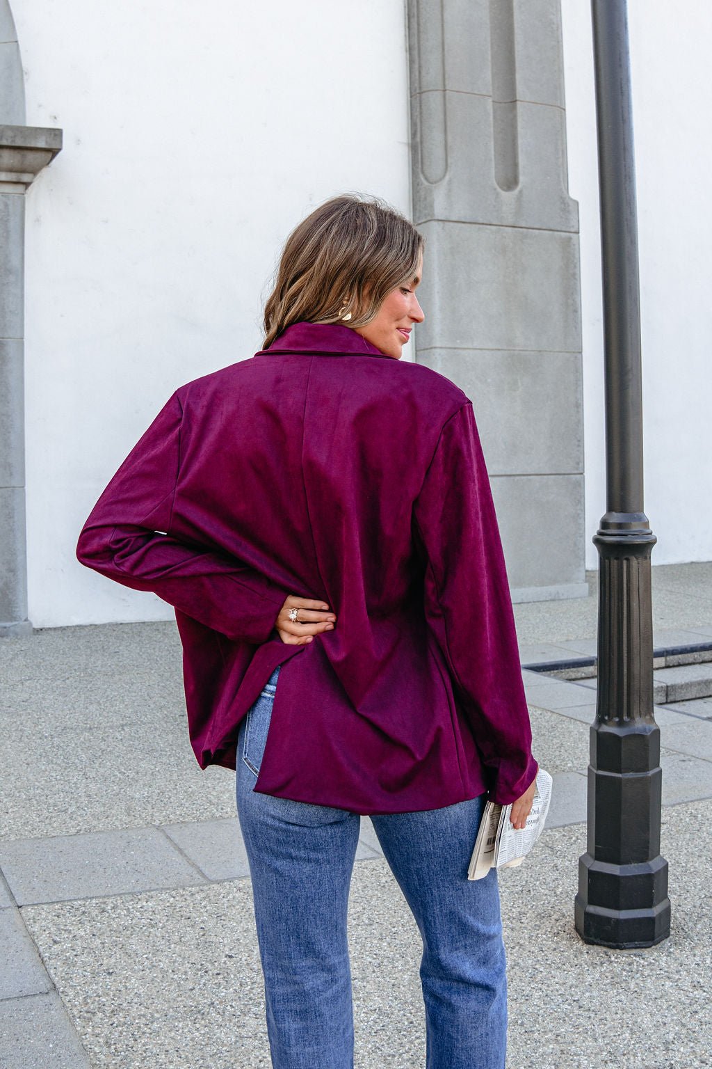 Woman in a wine suede SHE AND SKY ST1741 oversized blazer jacket stands outdoors, back turned, holding a book.