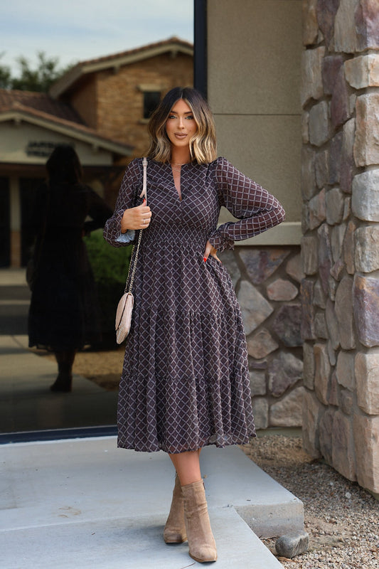A woman wears a brown Notched Long Sleeve Midi Dress with a white grid pattern, long sleeves, tan ankle boots, and a shoulder bag.