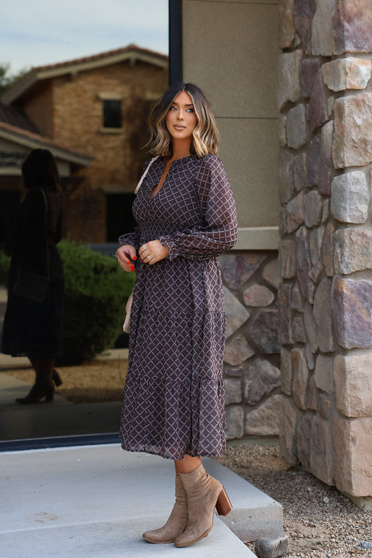 A person wearing a brown Notched Long Sleeve Midi Dress with a geometric pattern and tan ankle boots.
