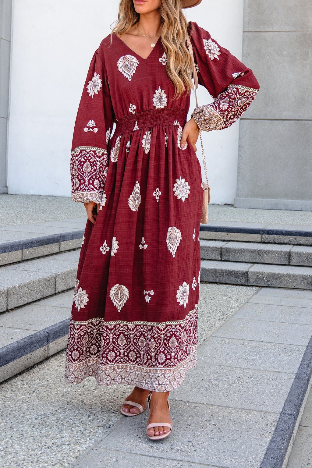 Woman wears the SHE AND SKY ST2144 brown printed long sleeve maxi dress, standing on outdoor steps in sandals.
