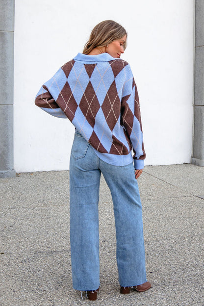 Woman standing outdoors in an oversized Sky Blue Argyle Ribbed Sweater with a collared V-neckline and light blue wide-leg jeans.