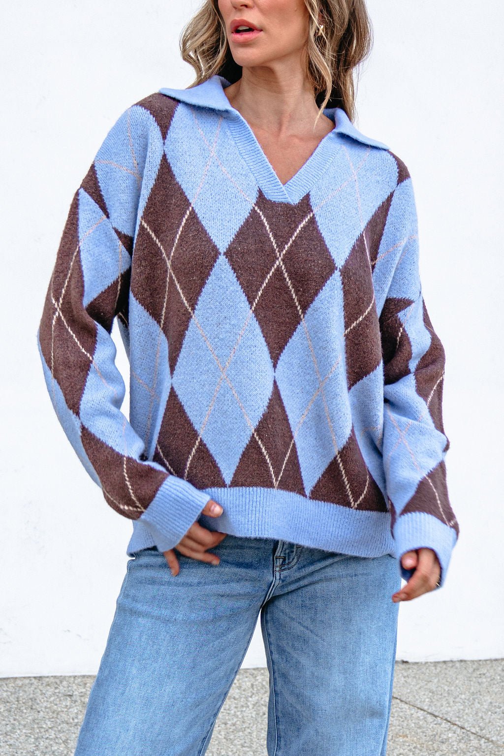 Woman in a Sky Blue Argyle Ribbed Sweater and light blue jeans, posing against a white background.