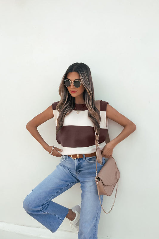 Woman in sunglasses poses against a white wall, wearing the Sleeveless Brown and Cream Striped Sweater - DOORBUSTER.