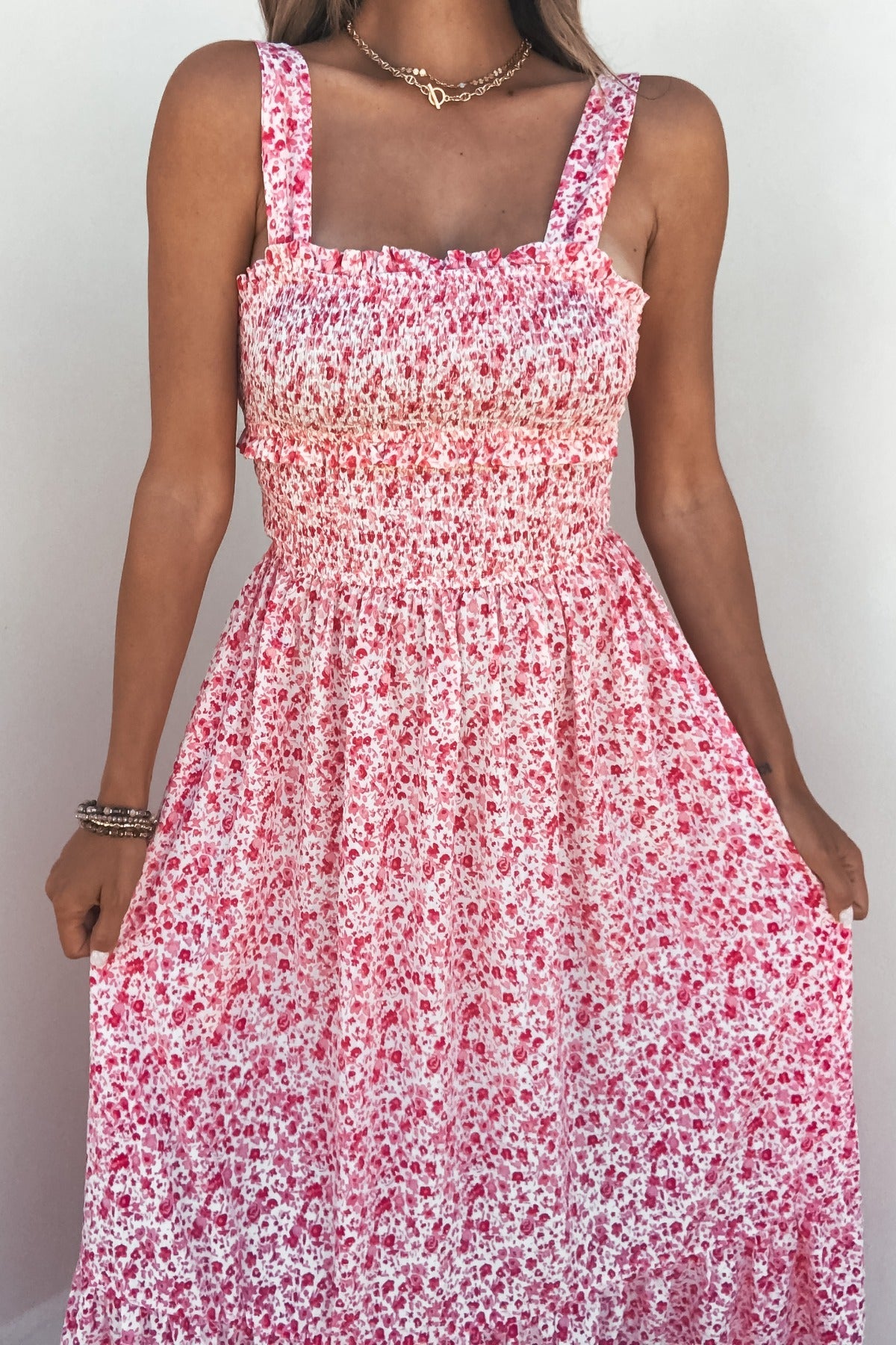 Woman wearing the Smocked Bow Tie Print Midi Dress in pink, featuring a sleeveless design and white bow tie print details.