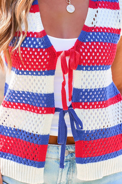 Woman in a Stars & Stripes Tie Front Sweater Vest over a white top and light jeans, accessorized with a round pendant necklace.
