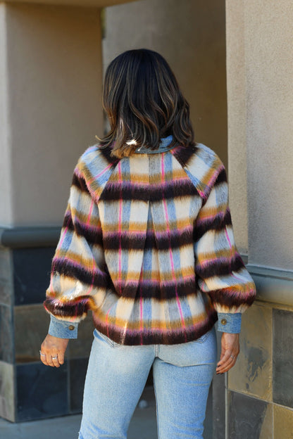 A woman in the Steve Madden Kaylen Multi Striped Jacket and light blue jeans stands facing away, ready for transitional weather.