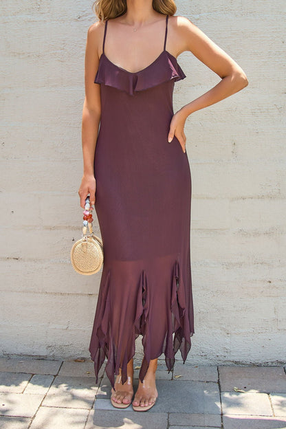 Woman in Steve Madden Mariane Midi Dress - Brown, barefoot with a straw purse, stands on pavement by a light wall.