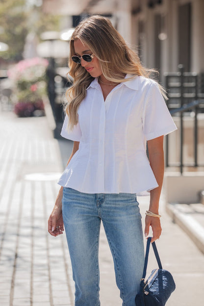 Woman with long blonde hair in sunglasses and blue jeans wearing the Steve Madden White Porter Top, standing outdoors.