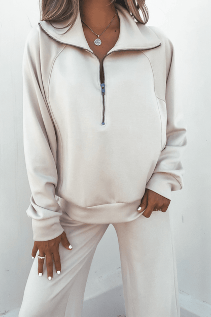 Woman in a cream zip-up and Stone Soft Cloud Scuba Sweatpants, accessorized with layered necklaces and rings, against a plain background.