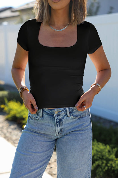 Woman outdoors in a Stretchy Black Double Lined Scoop Neck Top and light blue jeans, hands in her pockets.