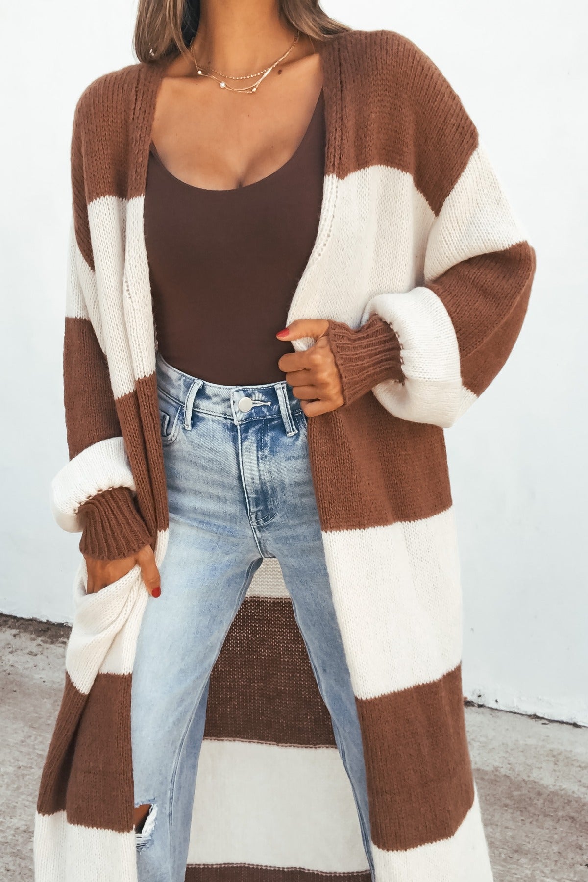 Model wears the Striped Duster Cardigan - Brown over a brown top and blue jeans against a plain white background.