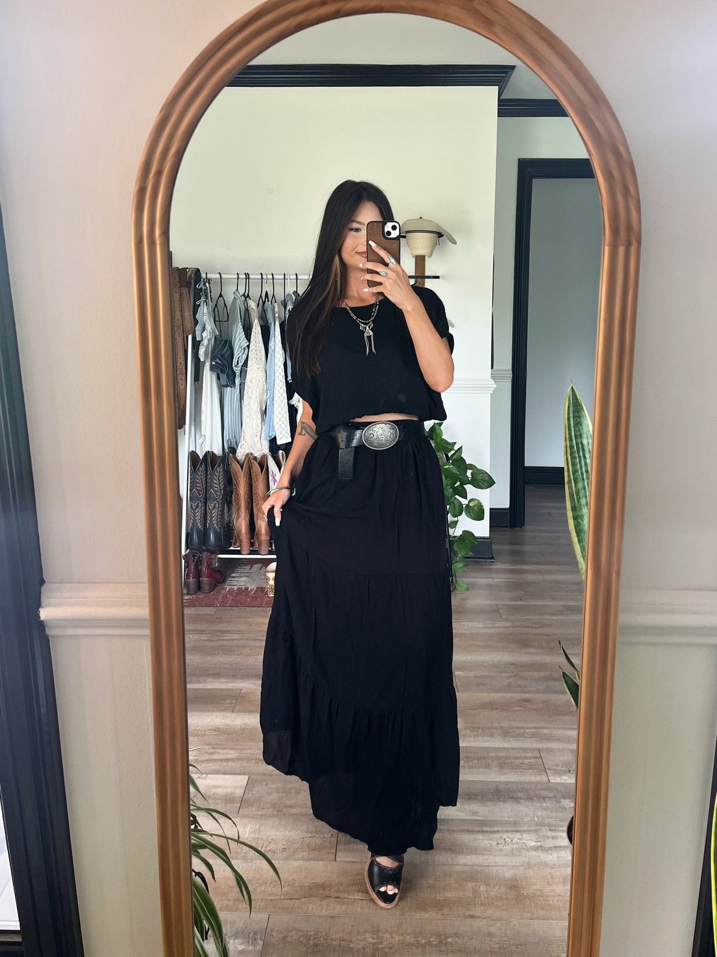 Woman wearing the Sunrise Short Sleeve Top & Maxi Skirt Black Set takes a mirror selfie in a stylish room.