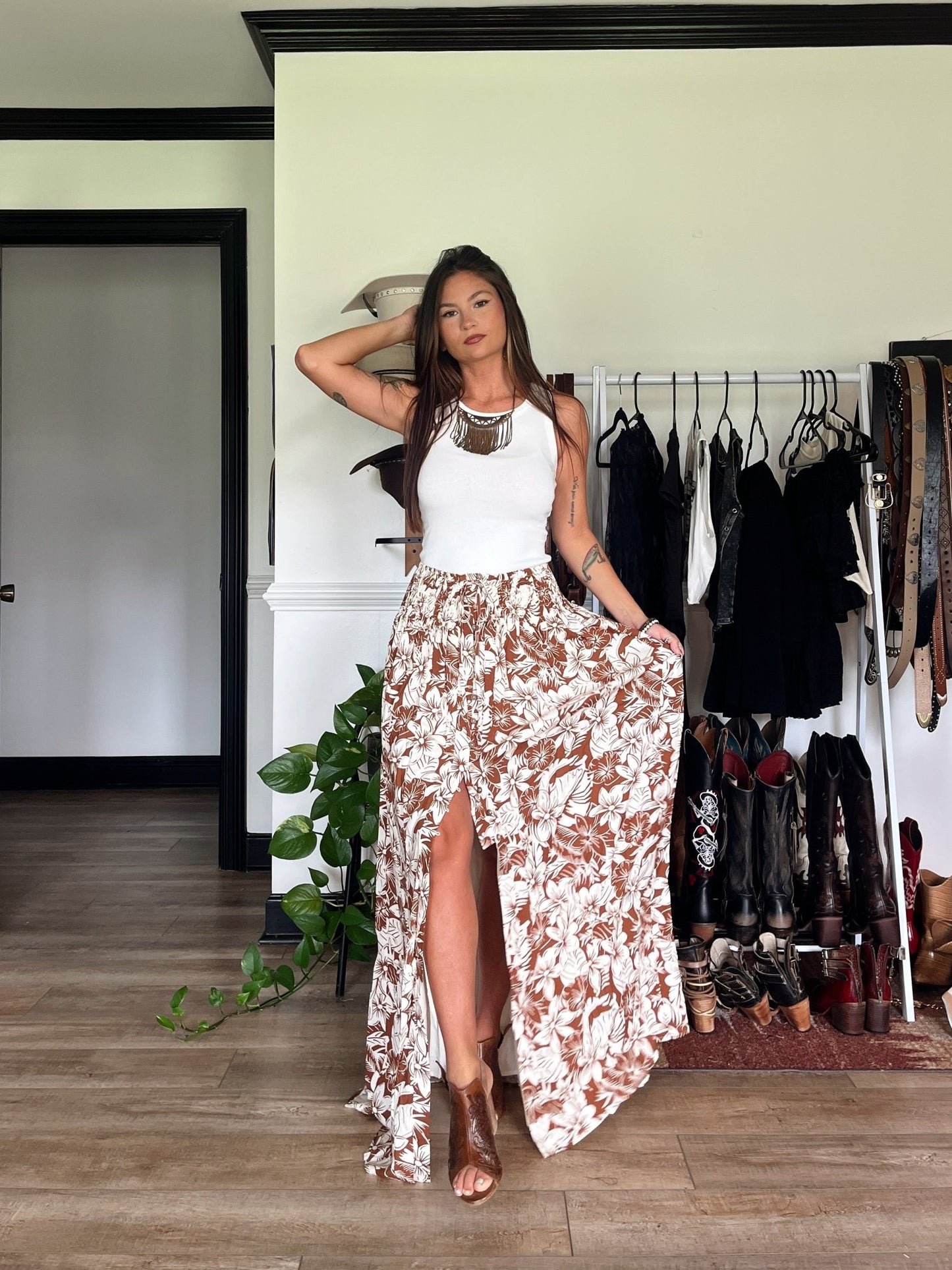 Woman indoors wearing the Taupe Floral Print Smocked Maxi Skirt - FINAL SALE with a chic boho vibe; clothes and shoes in background.