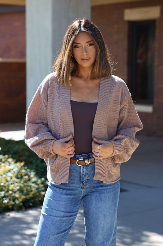 Woman with straight, shoulder-length hair wearing the Taupe Textured Open Front Cardigan, brown top, and blue jeans outdoors.