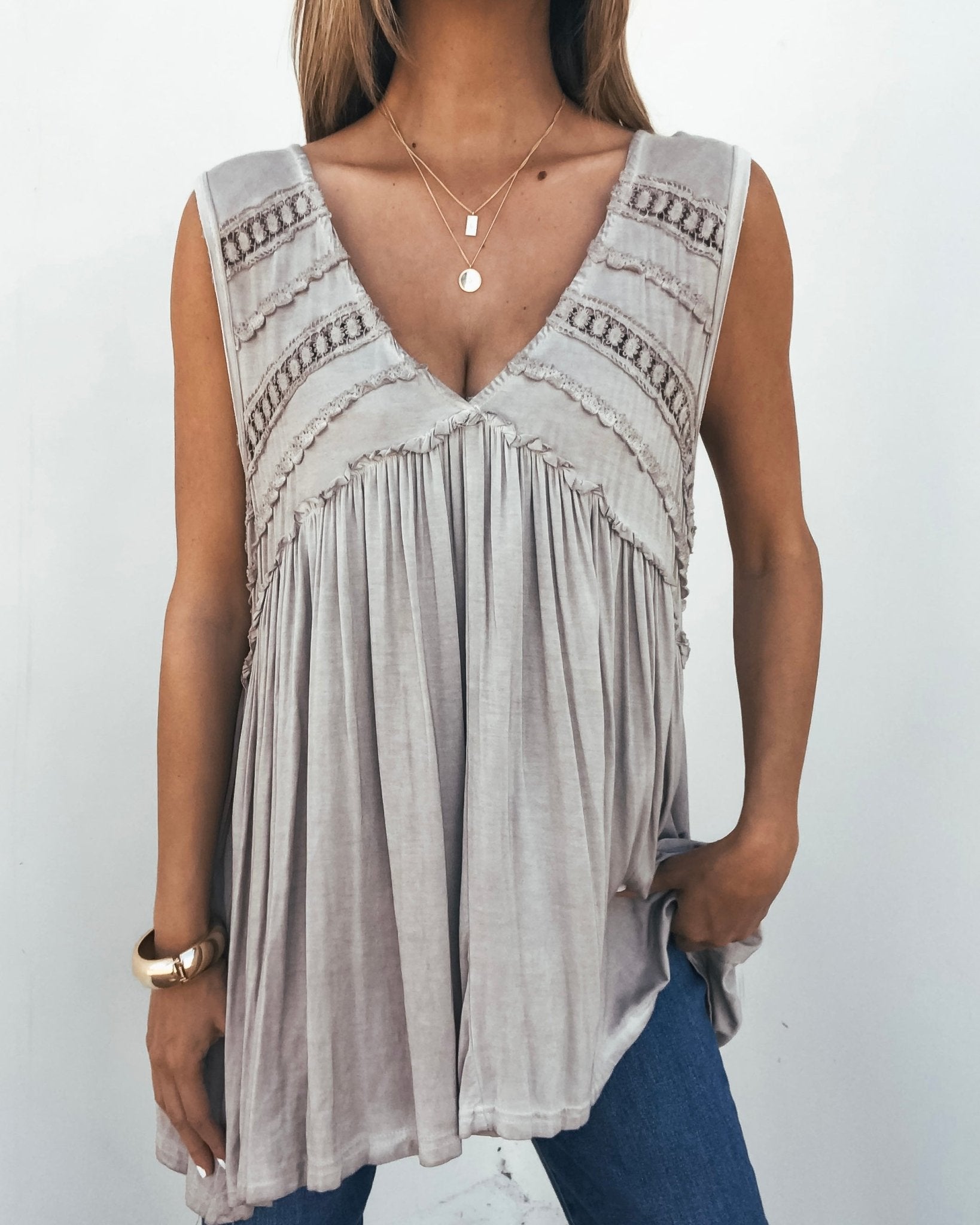 Woman in a Taupe V Neck Flowy Top—flowy, crochet ruffle details; styled with jeans and layered necklaces for a chic, bump-friendly look.