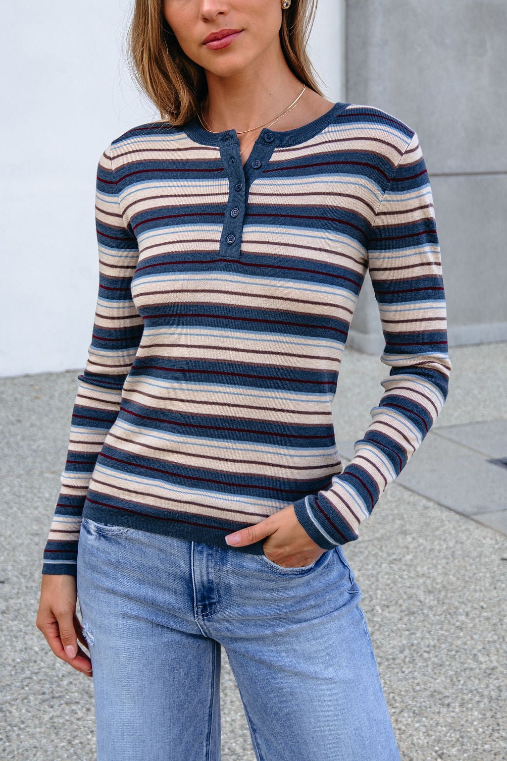 Woman wearing a Teal Striped Henley Long Sleeve Top with a button-up front, paired with light blue jeans.