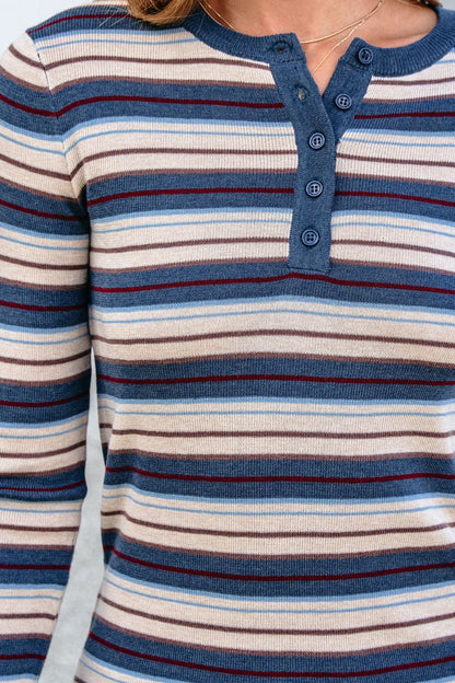 Someone wears the Teal Striped Henley Long Sleeve Top featuring a relaxed fit and four blue, cream, and maroon button front details.