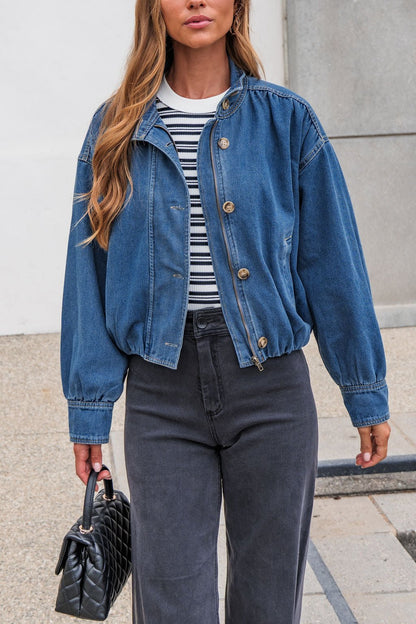Woman in The Dakota Denim Jacket, black jeans, and striped shirt carries a quilted handbag on a city sidewalk.