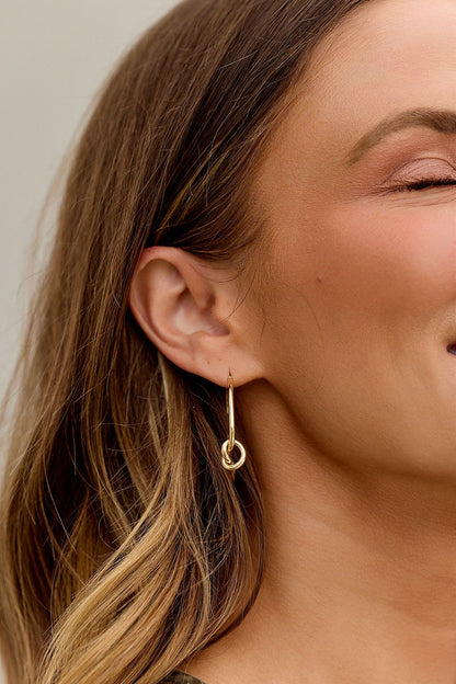Close-up of a woman's ear with The Elara Hoop Earrings - Gold and wavy brown hair.