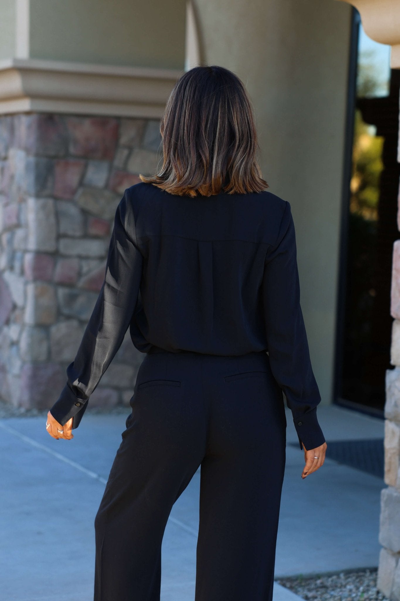 A woman with shoulder-length brown hair wears the Thread and Supply Black Button Down Top, ideal for casual outdoor outfits.