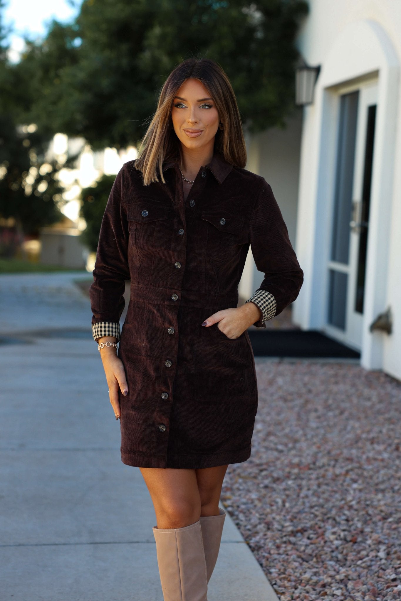 A woman wears the Thread and Supply Brown Corduroy Mini Dress, smiling outdoors on a sidewalk.