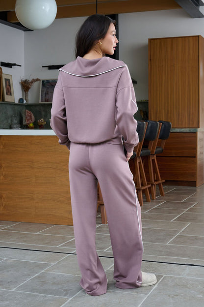 A woman in Thread and Supply Mocha Wide Leg Drawstring Pants stands indoors, facing away in a modern kitchen with wooden cabinets.