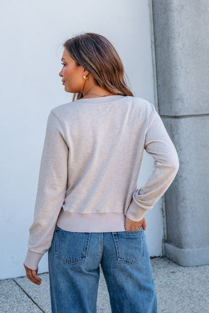 Woman outdoors wearing the Thread and Supply Taupe Monica Sweater Cardigan and blue jeans, one hand on her hip.