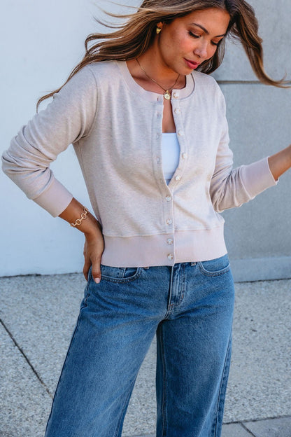 Woman in Thread and Supply Taupe Monica Sweater Cardigan over white top and blue jeans, standing outdoors with hand on hip.