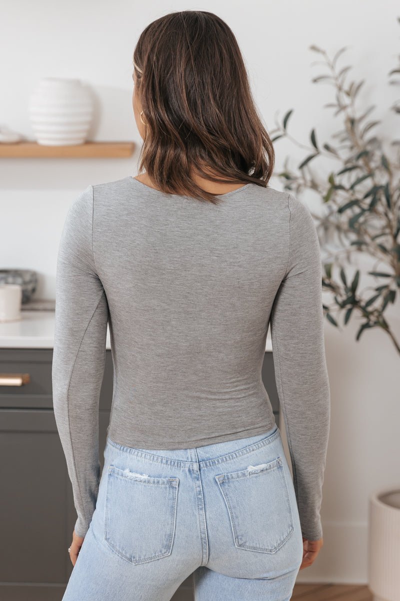 Woman with shoulder-length brown hair wears an Ultra-Stretchy Scoop Neck Top in grey and light blue jeans, perfect for layering.