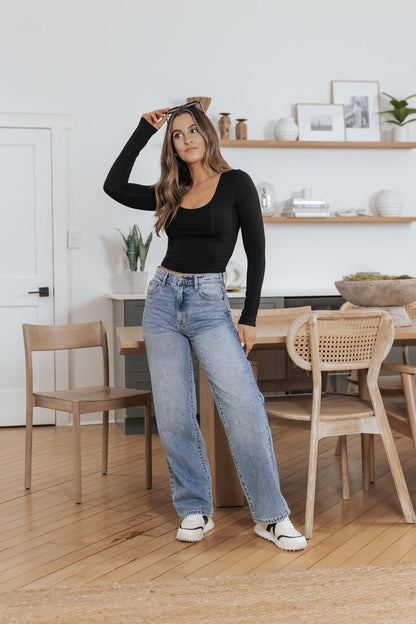 Woman in an Ultra-Stretchy Scoop Neck Top - BLACK and blue jeans adds chic style with sunglasses in a modern dining room.