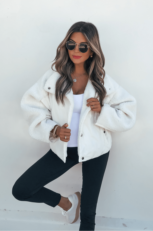 Woman in sunglasses models a Vintage Havana Ivory Sherpa Fleece Jacket with black pants, white sneakers, and red lipstick.