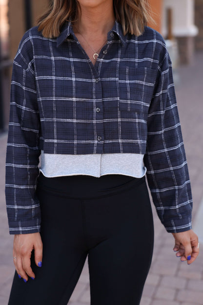 Woman wearing a Vintage Havana Midnight Plaid Flannel Shirt and black leggings, standing outdoors on a paved walkway.