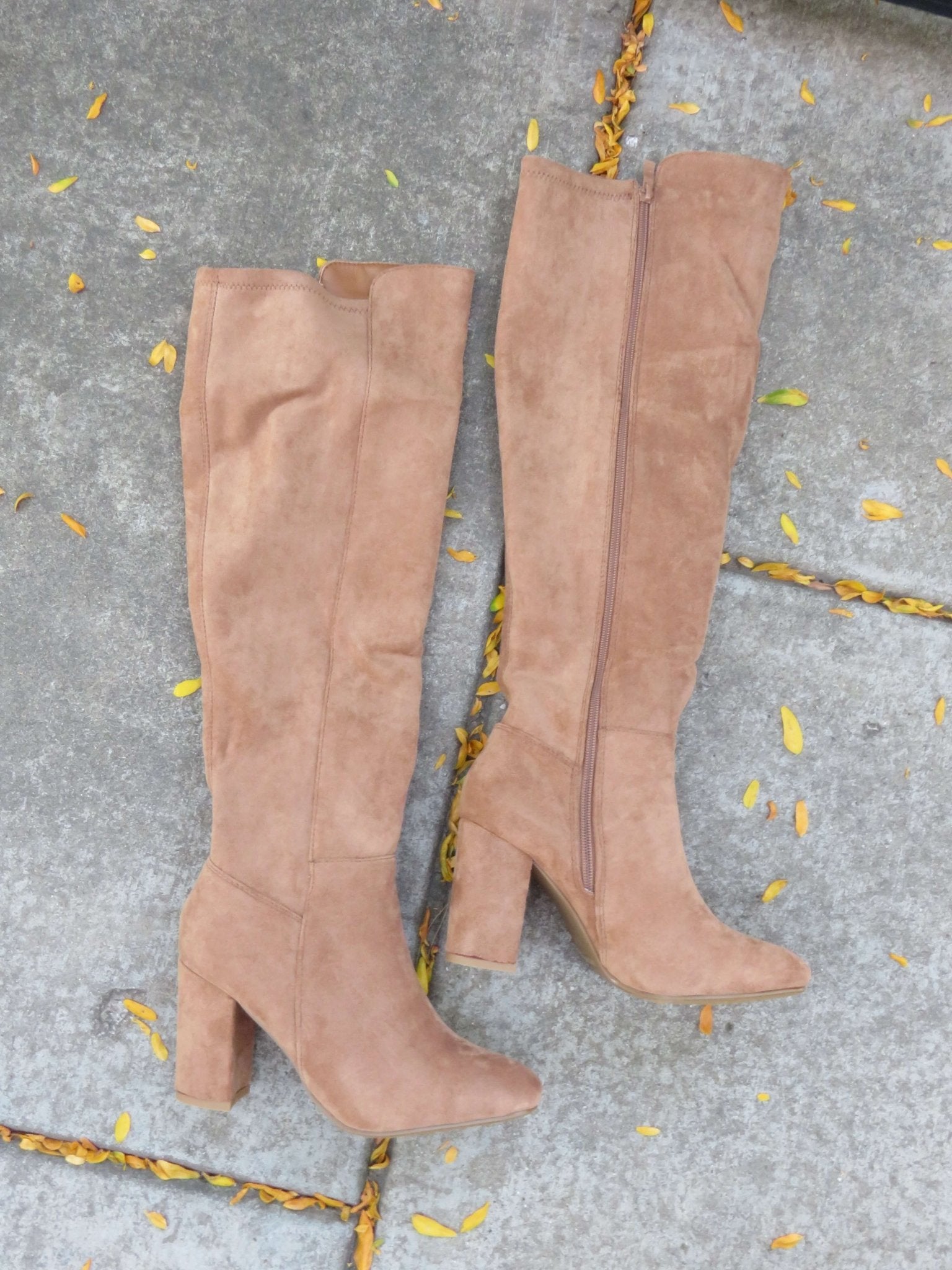 Whisky Camel Suede Heeled Knee High Boots on a concrete surface scattered with yellow leaves.