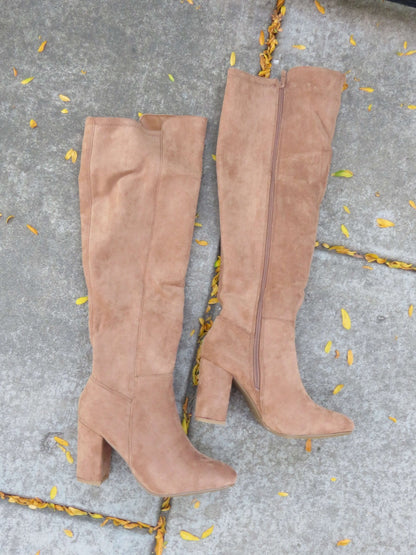 Whisky Camel Suede Heeled Knee High Boots on a concrete surface scattered with yellow leaves.