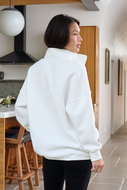 A woman wears the White Collared Button Up Pullover Sweatshirt indoors, with a modern kitchen visible in the background.