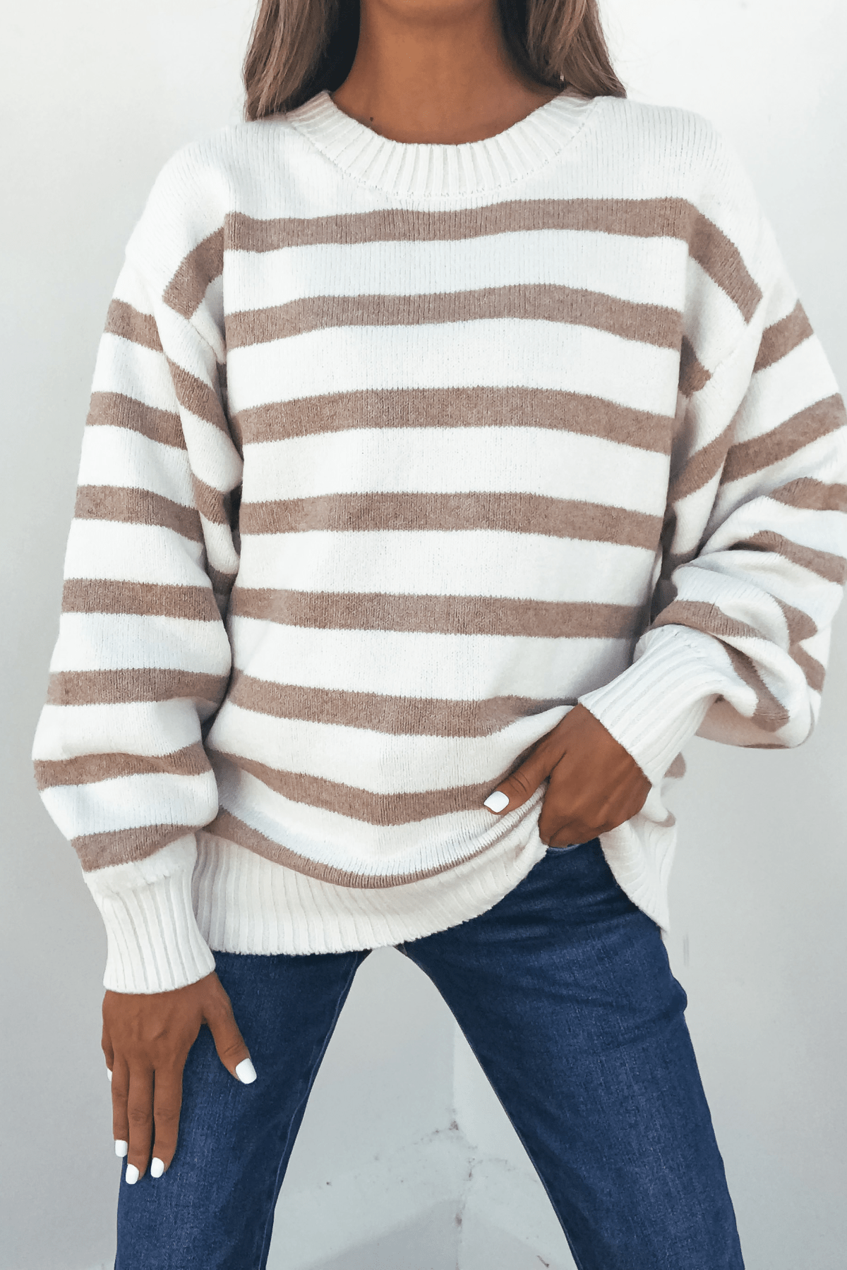 Woman wearing the Willow Cream Stripe Ribbed Sweater with blue jeans against a plain background.