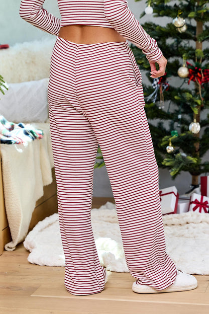 Person wearing Wine Striped Lounge Pants stands near a decorated Christmas tree and presents on a wooden floor.