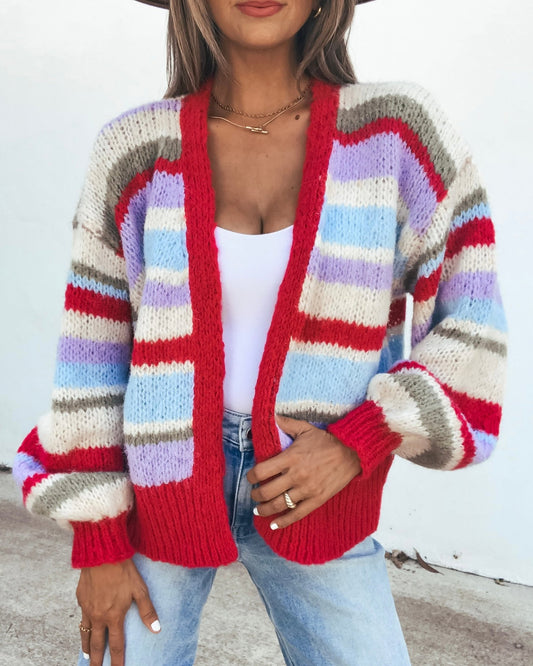 Person wearing a Striped Cardigan - Fuchsia with chunky horizontal stripes in red, white, lavender, and light blue featuring balloon sleeves.