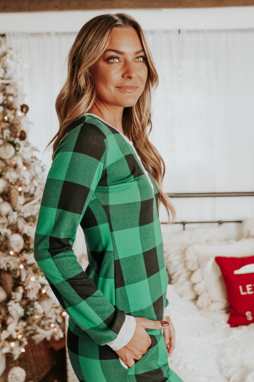 Woman wears the Christmas Morning Green Plaid Pajama Set, standing indoors by a decorated Christmas tree and holiday decor.