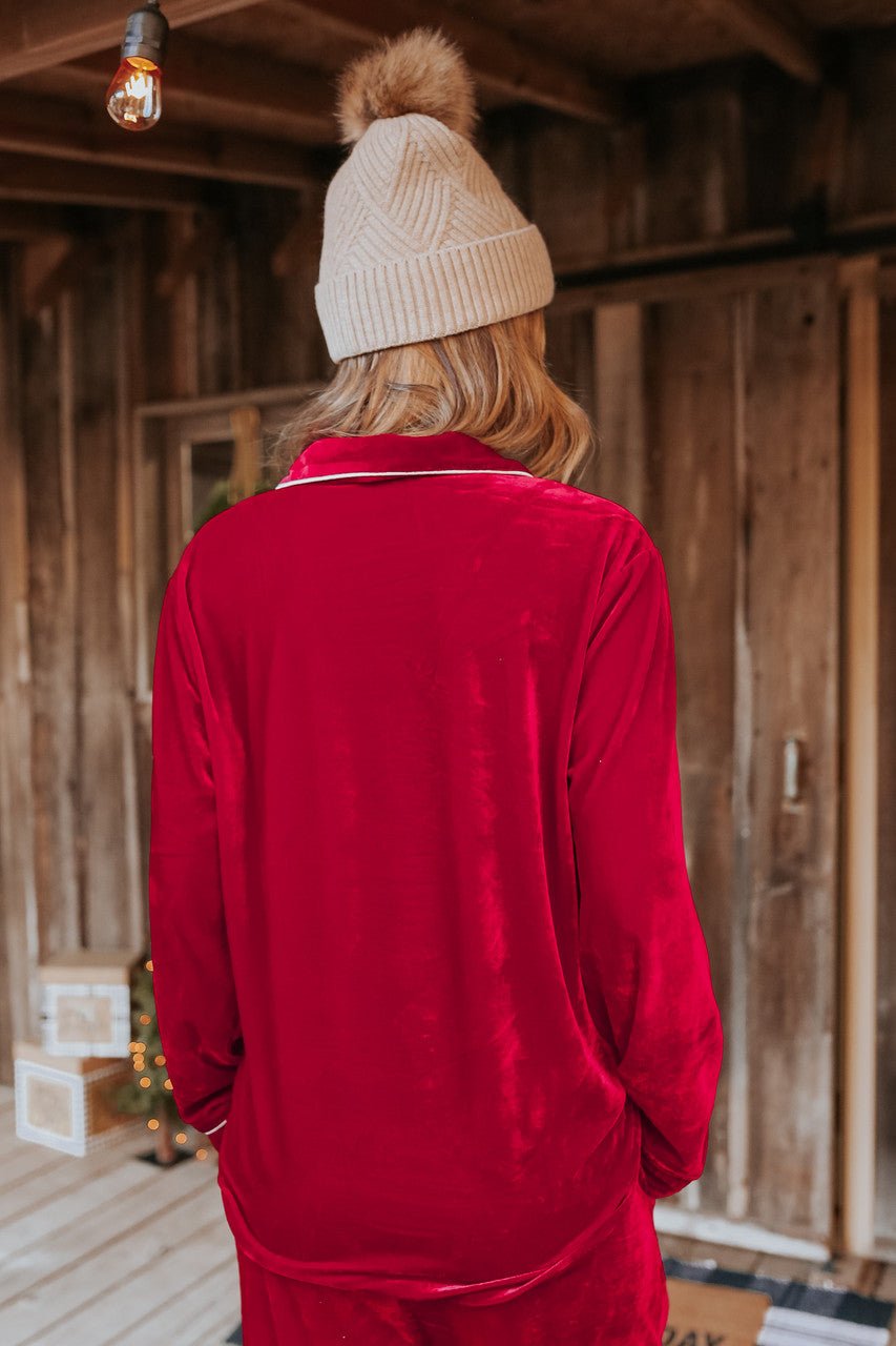 Someone in the North Pole Burgundy Velvet Pajama Set stands with their back to the camera on a rustic wooden porch.