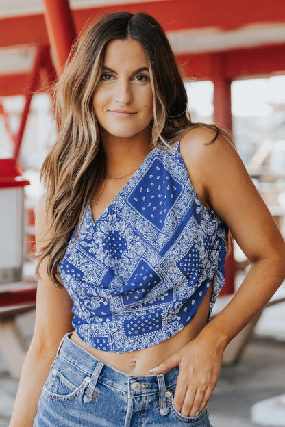 Woman with long brown hair wears the Out West Blue Bandana Print Sleeveless Cowl Neck Top, smiling outdoors.