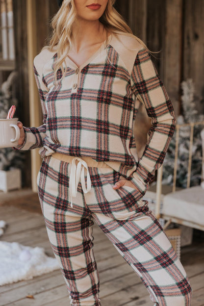 Woman in Taupe Tartan Plaid Jogger Pajama Pants - FINAL SALE holding a mug with candy canes on a winter-decorated porch.